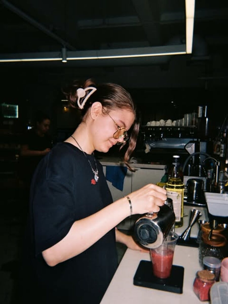 Бариста Atlas cafe готовит напиток за стойкой